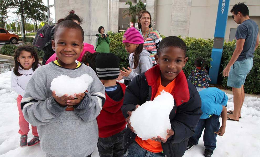 Children joyfully playing in the snow at Tri-Rail's Winter Wonderland.