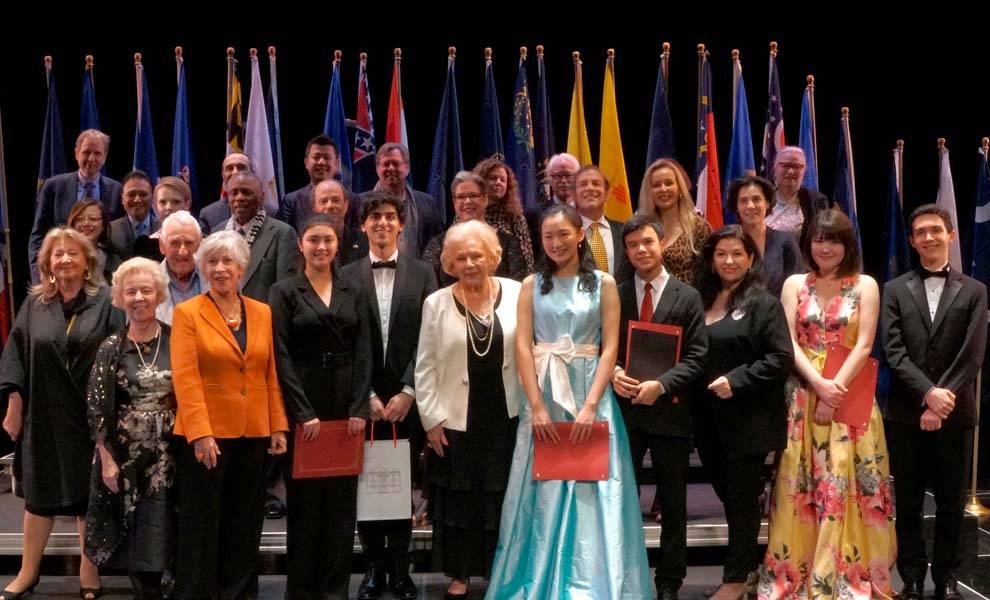 Un grupo diverso de personas orgullosas en el escenario del concurso de piano Chopin.