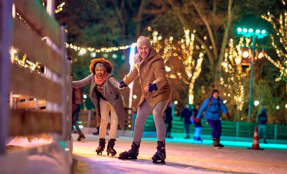 A man and woman ice skating at night.