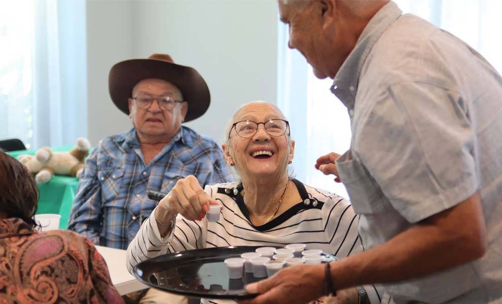 Una mujer mayor sonríe cálidamente mientras sostiene un café en el evento de Acción de Gracias de Kiwanis.
