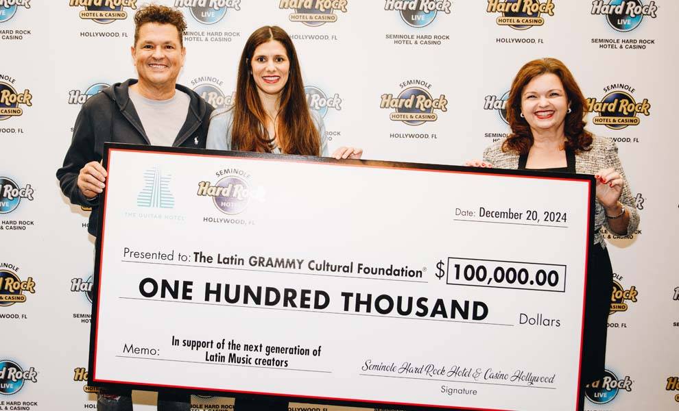 Three individuals proudly display a check for $100,000, for the Latin GRAMMY Cultural Foundation.