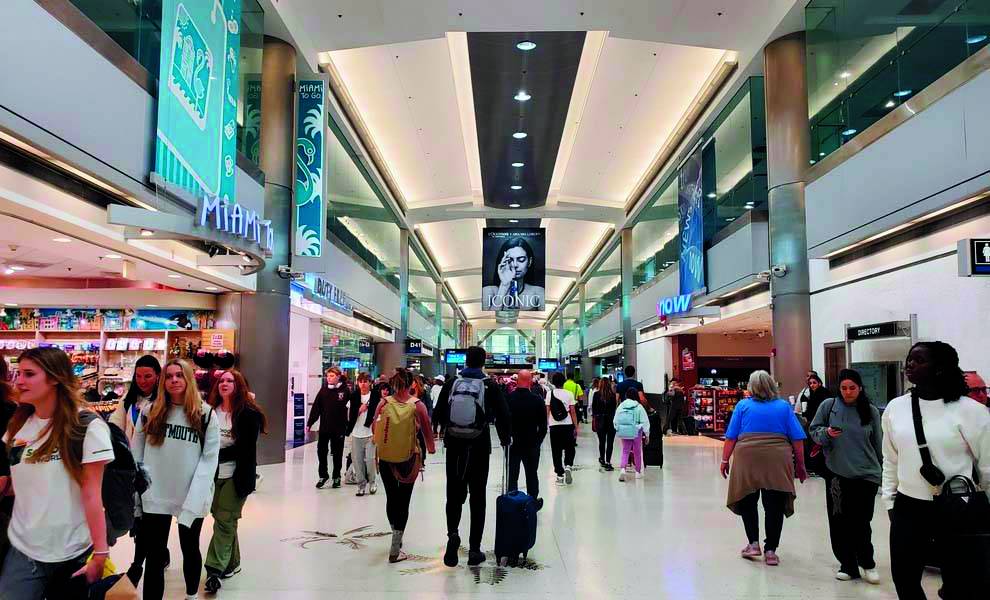 Un grupo diverso de viajeros navegando por una terminal de aeropuerto, cada uno llevando equipaje mientras avanzan hacia sus destinos.