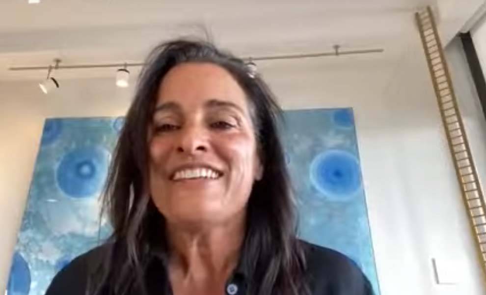 Avra Jain smiles joyfully in front of a vibrant painting.