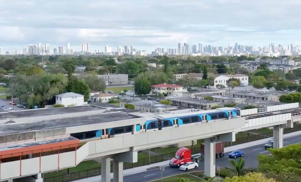 Un tren cruza un puente con un vibrante horizonte de la ciudad visible en el fondo, mostrando la vida urbana y el transporte.
