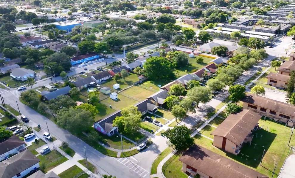 Aerial view of a neighborhood showcasing houses surrounded by lush green trees and well-maintained streets.