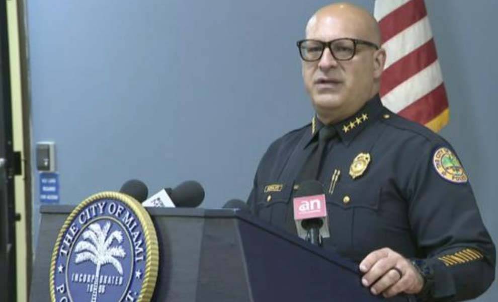 A police officer wearing glasses addresses an audience from a podium, conveying important information.