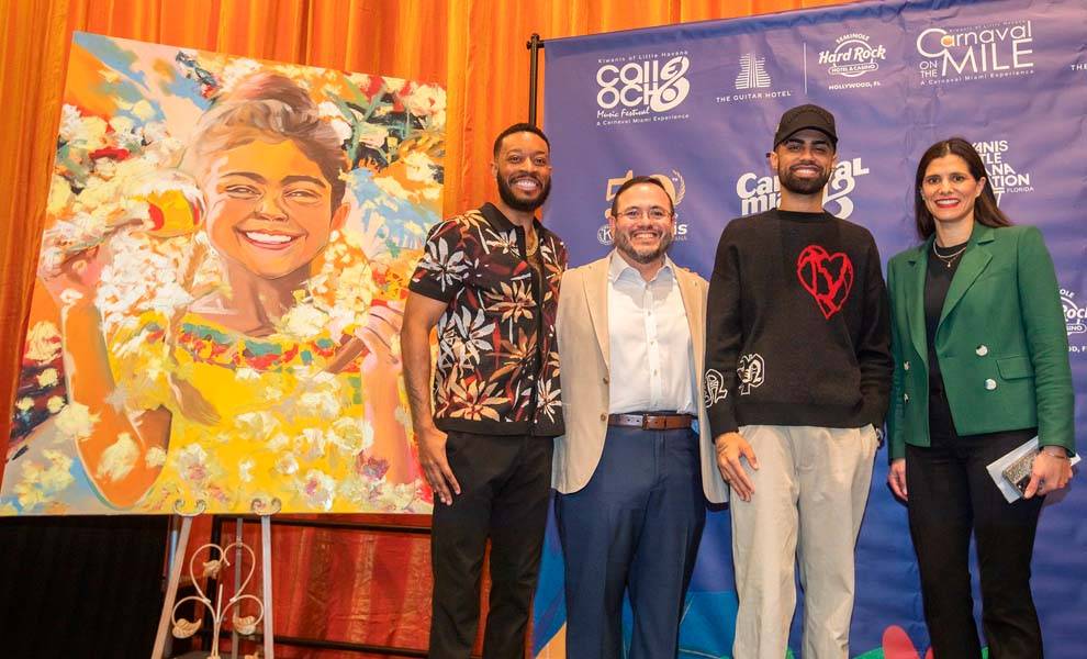 Four individuals stand beside a large painting, engaged in conversation and admiring the artwork displayed.