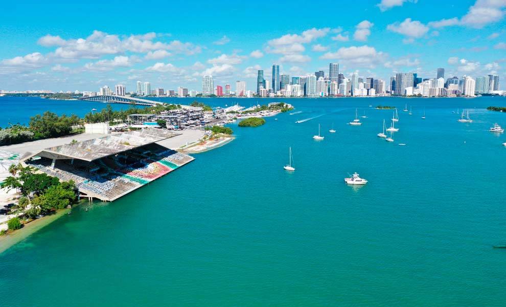 Vista aérea del Miami Marine Stadium contra un cielo azul claro y las brillantes aguas debajo.