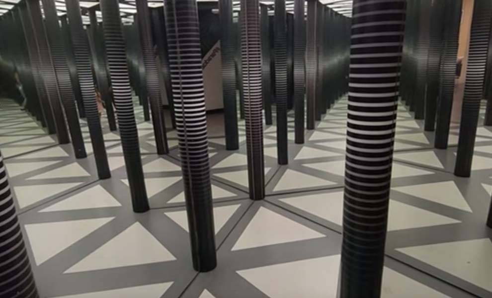 A room filled with numerous black poles intersected by white lines, creating a striking visual contrast at the Paradox Museum.