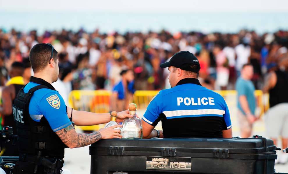 Two police officers stand beside a large Spring Break crowd.