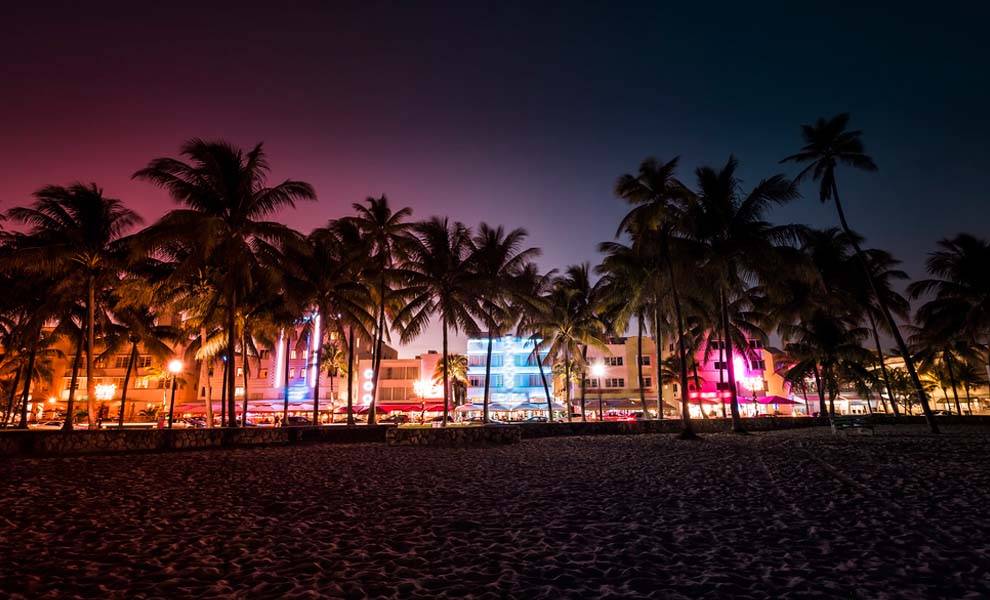 Fotografía nocturna de Miami Beach, que muestra las vibrantes luces de la ciudad.