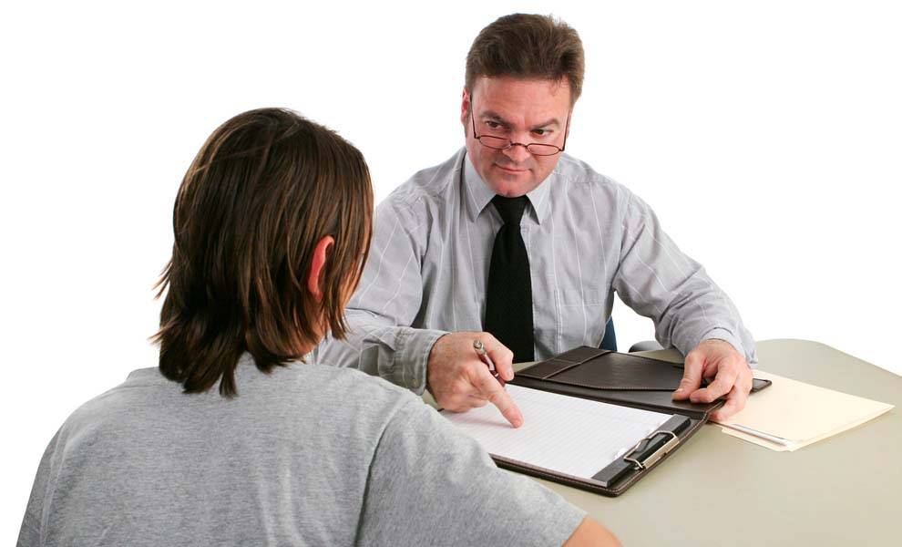 A man sits at a desk, engaging with a young boy, fostering a moment of learning and connection between them.
