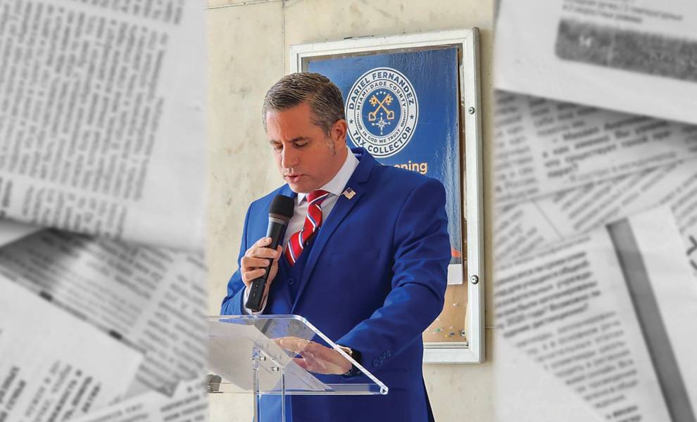 Dariel Fernández, recaudador de impuestos de Miami-Dade, con un traje azul, habla por un micrófono.