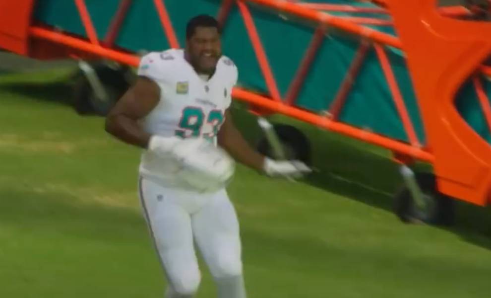 Miami Dolphins football player wearing a white uniform with the number 93, appearing excited or celebrating on the field near an orange sideline structure.