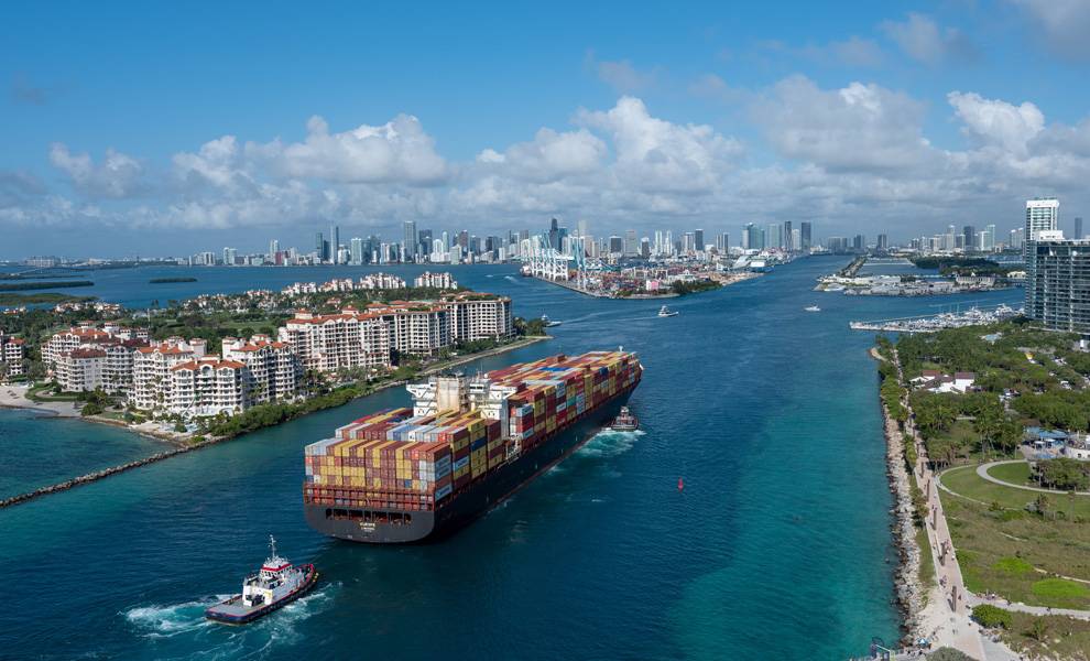 A large container ship navigates through the water at PortMiami.