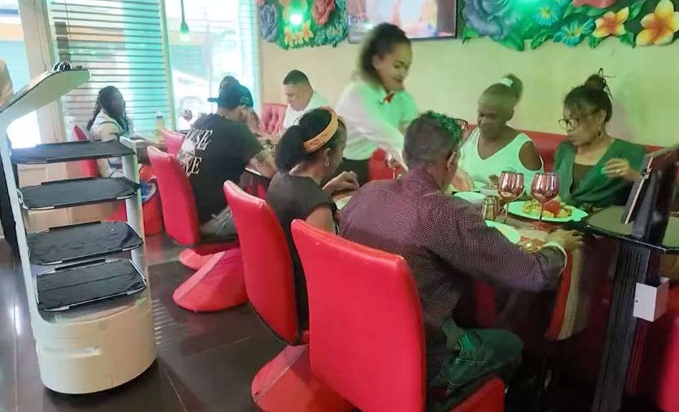Comensales disfrutando de sus comidas en el restaurante Doña Alicia con un robot de fondo.