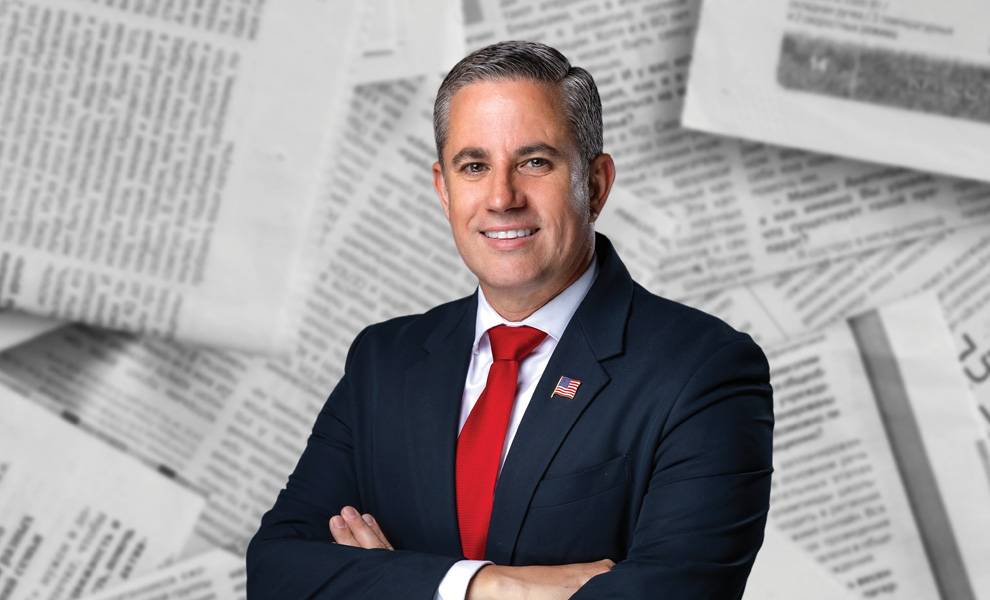 Dariel Fernandez in a blue suit and red tie stands confidently.