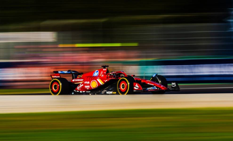 Un coche de carreras rojo de Fórmula 1 avanza a toda velocidad por la pista, mostrando su elegante diseño y movimiento dinámico.