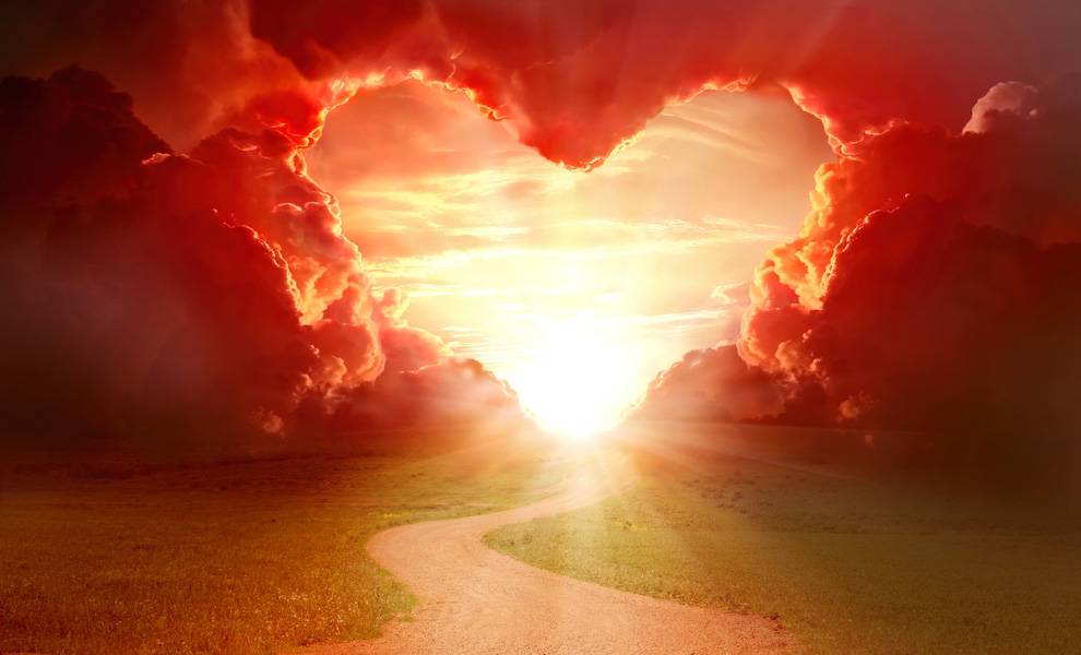 A winding path leads towards a fluffy heart-shaped cloud in a clear blue sky.