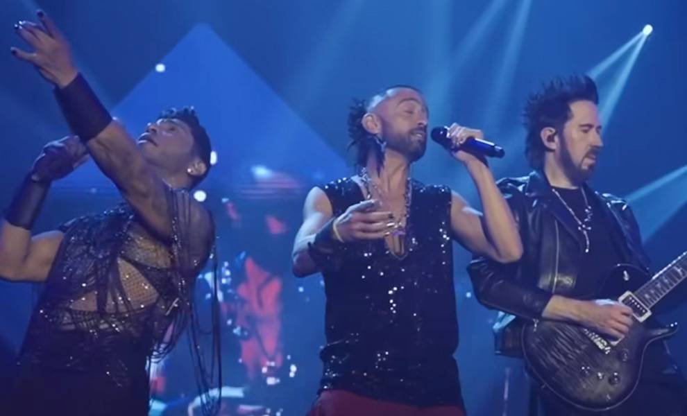 Camila con atuendos negros interpretando música mientras canta y toca guitarras en el escenario.