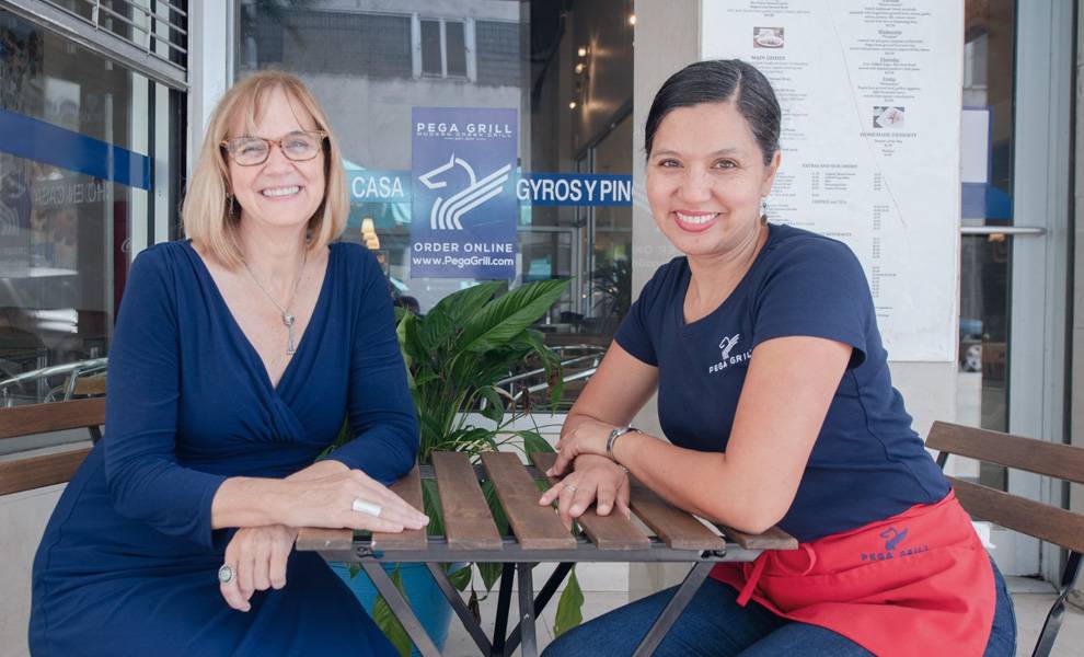 Eileen Higgins with the owner of Pega Grill seated at a table outside.
