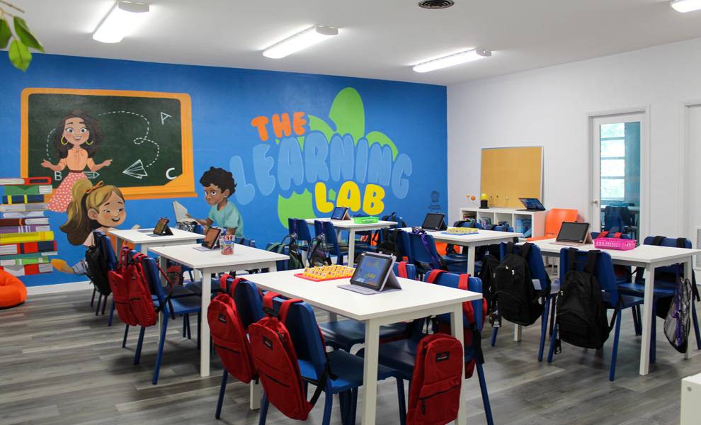 Un aula con filas de escritorios y sillas dispuestas para que los estudiantes se sienten y realicen actividades de aprendizaje.