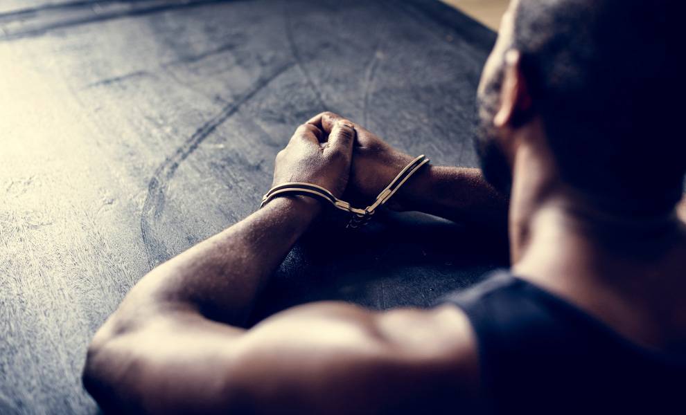 Un hombre con esposas está sentado en una mesa.