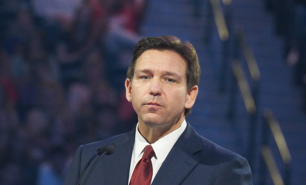 A man in a suit and tie delivers a speech at a podium during a formal event.