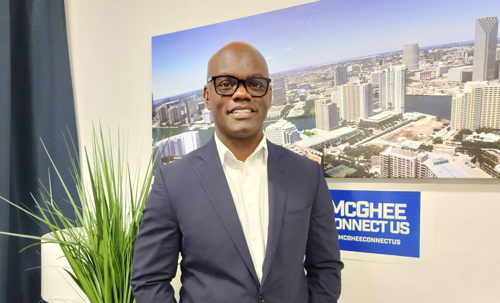 La comisionada Kionne L. McGhee con una camisa blanca y una chaqueta azul con una imagen de la ciudad de Miami de fondo.