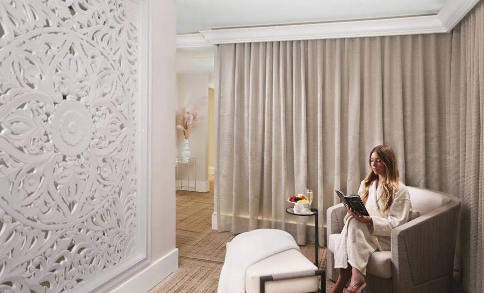 Una mujer en bata sentada leyendo un menú en un spa de lujo en Miami.