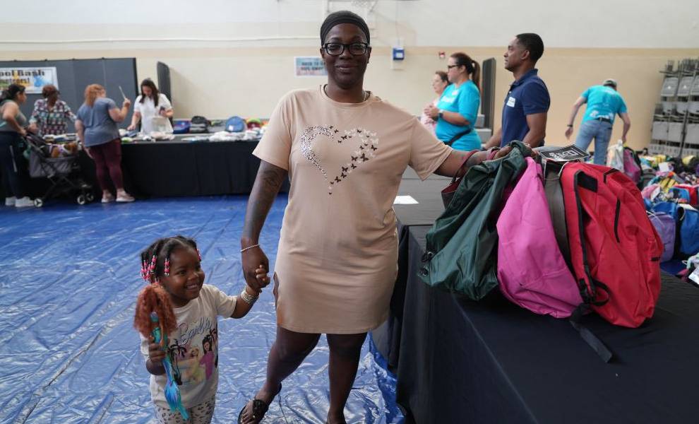 Una madre y su hijo sonríen mientras reciben útiles escolares de The Caring Place.