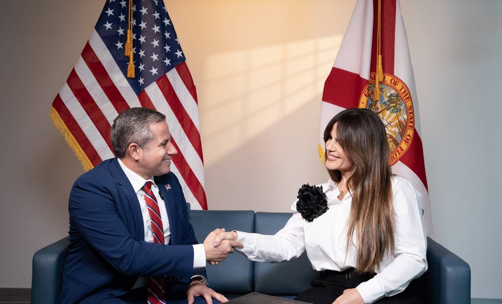 Miami-Dade County Tax Collector Dariel Fernandez sitting on a couch shaking hands with Calle Ocho News Editor In Chief Rosi Rosell.