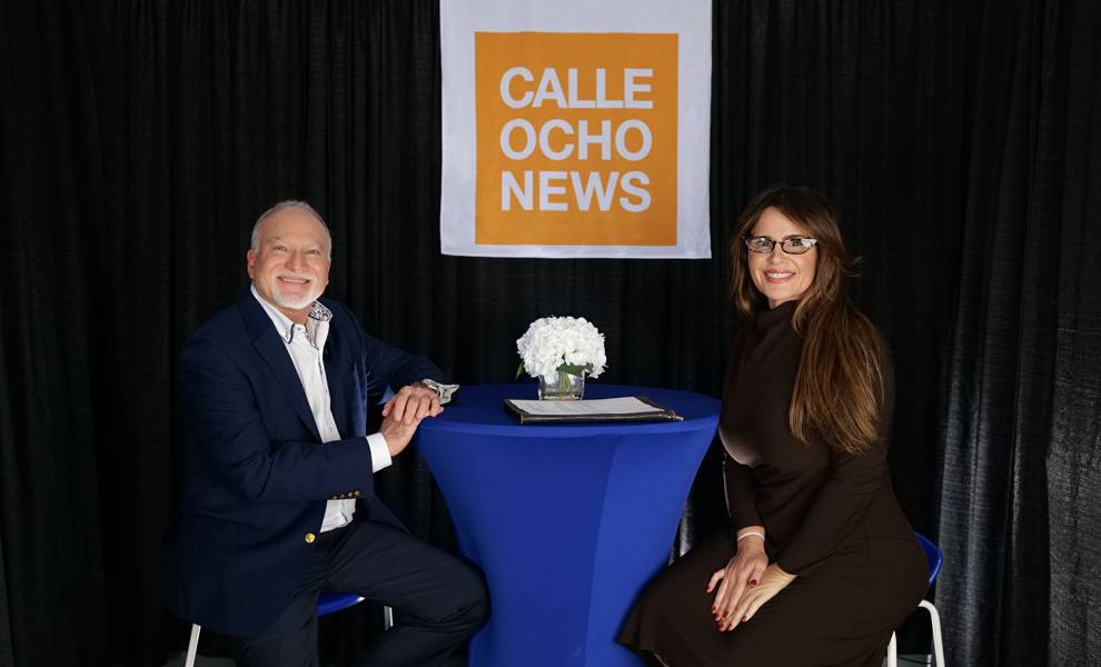 MDC Campus President Oscar Loynaz sitting at a blue table with Calle Ocho News Editor In Chief Rosi Rosell.