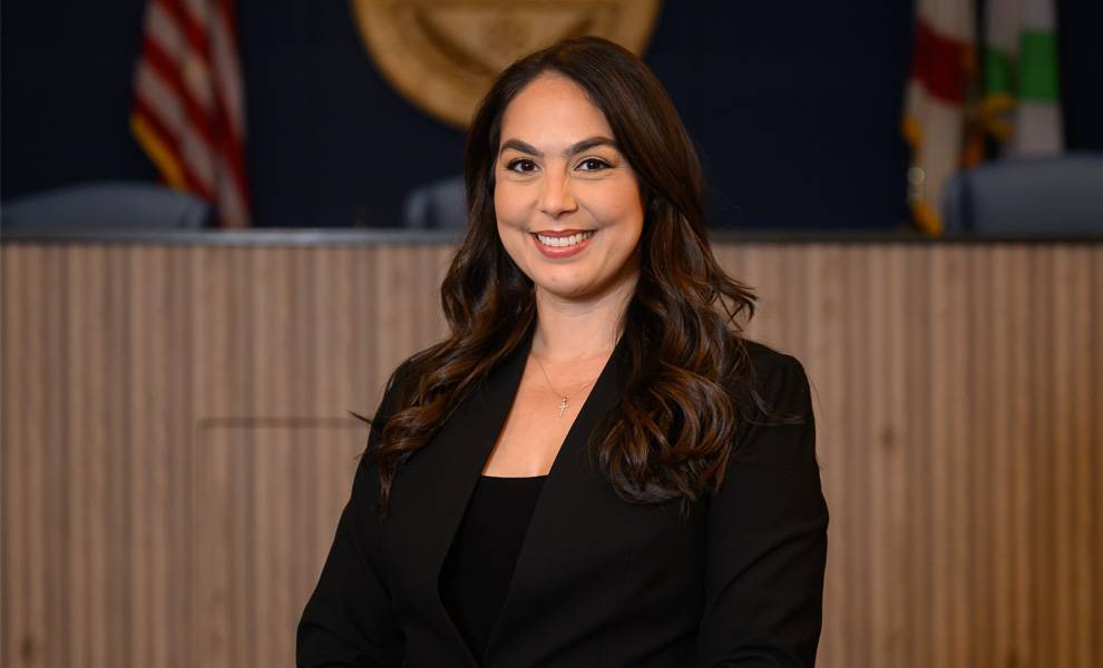 Commissioner Natalie Milian Orbis inside City Hall wearing a black suit.