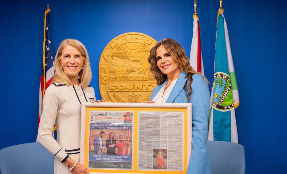 La comisionada del condado de Miami-Dade, Vicky Lopez, sostiene un ejemplar enmarcado de Calle Ocho News junto a la editora en jefe de Calle Ocho News, Rosi Rosell.