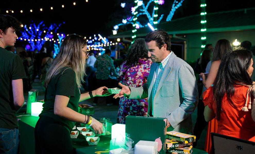 A vendor at Feast for the Beasts giving food to a guest.