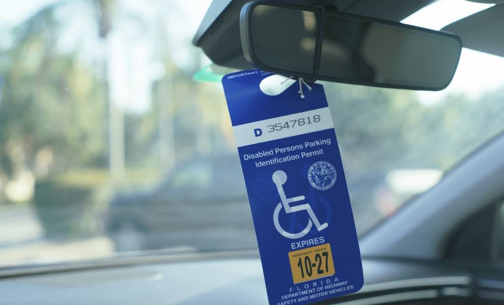 Placa azul para discapacitados colgada en el espejo retrovisor del coche.