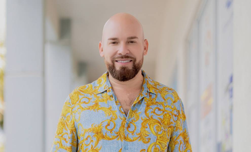Cuban American publicist and press chief Maykel Pérez in a blue and gold button up shirt.