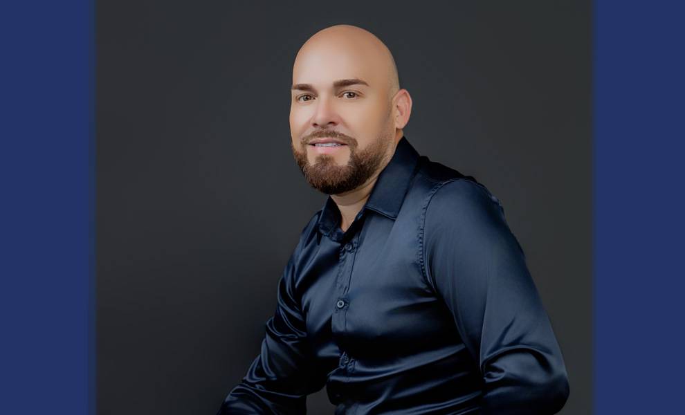 Cuban American publicist and press chief Maykel Pérez in a blue button up shirt.