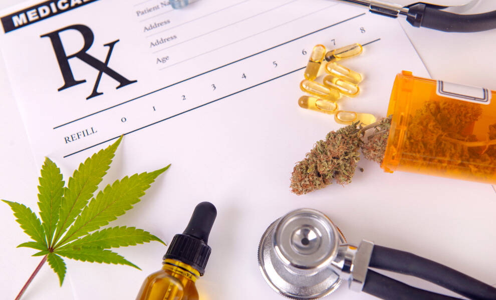 A close-up of a medical prescription form labeled “Rx” alongside marijuana-related items, including a marijuana leaf, a small jar of oil with a dropper, capsules, a prescription pill bottle with cannabis buds, and a stethoscope.