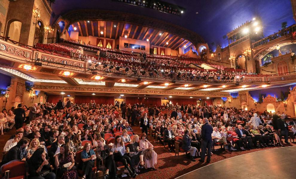 Vista de gran angular de un teatro grande y ornamentado, repleto de público sentado, que incluye la platea y el balcón, durante el Festival de Cine de Miami.