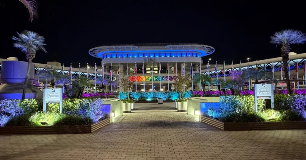 The Central Garden area at Miami International Airport is illuminated at night with colorful blue, purple, and green lighting.