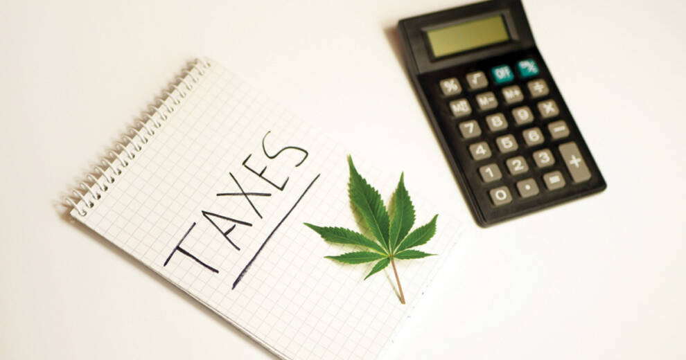 A spiral notebook labeled "TAXES" sits next to a green cannabis leaf and a calculator on a white surface. The image represents cannabis taxation, financial planning, and tax compliance within the legal cannabis industry.