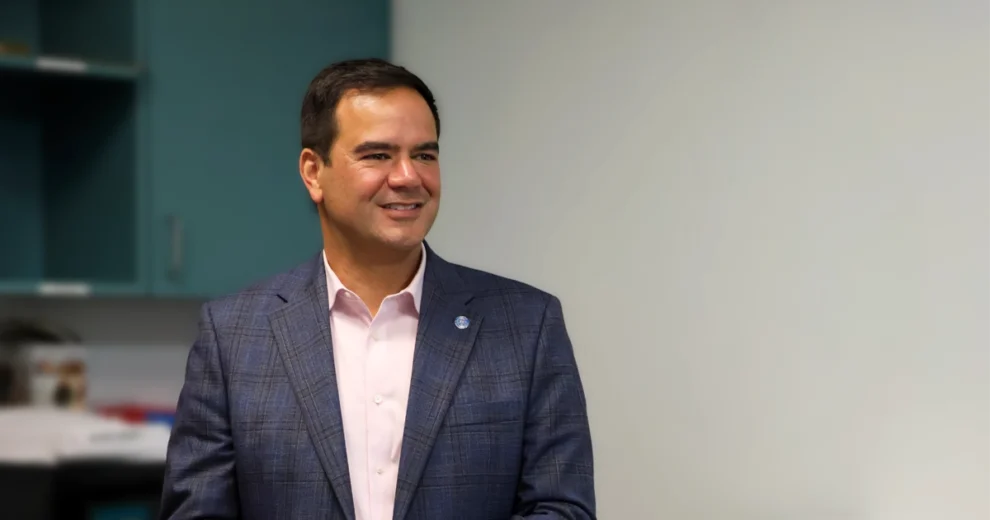 District 4 Commissioner Ralph “Rafael” Rosado on C.A.S.A.: Building Community, Adaptability, Safety, and Affordability Across the City of Miami One Neighborhood at a Time 1 District 4 Commissioner Ralph “Rafael” Rosado smiles while standing indoors in a blazer and light pink shirt, with teal cabinets and a neutral wall in the background.