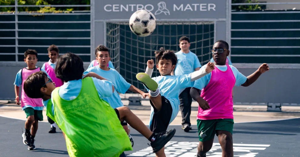 Un grupo de niños participa en un partido de fútbol en una cancha al aire libre en el Centro Mater.