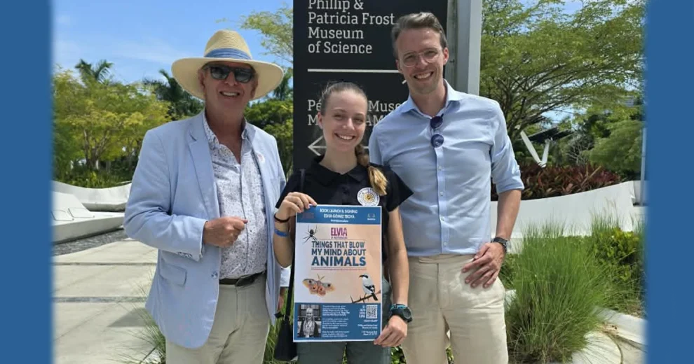 Elvia Gomez Troya poses with two adults outside the Phillip & Patricia Frost Museum of Science in Miami while holding a poster for Things That Blow My Mind About Animals.