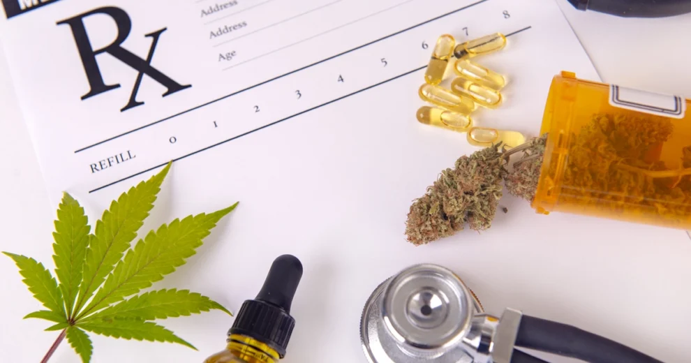 A medical cannabis-themed flat lay featuring a prescription form marked with an "Rx" symbol, a cannabis leaf, a prescription pill bottle containing dried cannabis flower, capsules, a dropper bottle of cannabis oil, and a stethoscope.