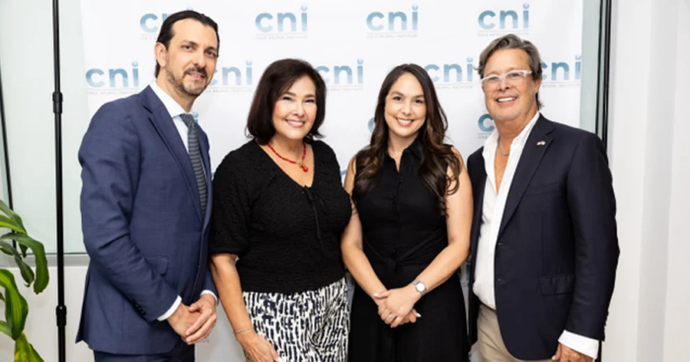 Four adults pose together in front of a CNI-branded backdrop at an event.