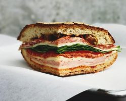 A ham and vegetable-loaded Cuban sandwich placed on a napkin.