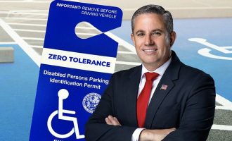 Miami-Dade Tax Collector Dariel Fernandez with a handicap parking placard in the background.
